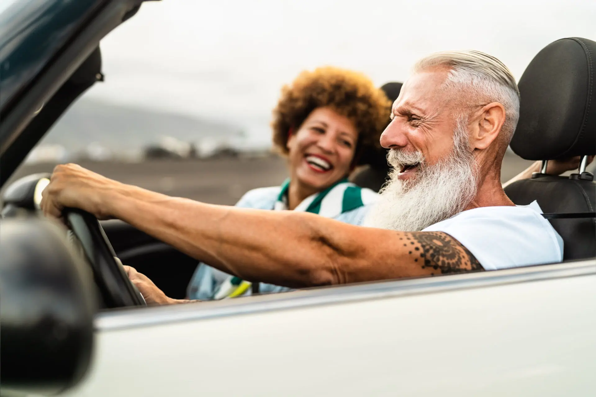 Senior couple having fun driving convertible car.